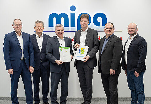El administrador del distrito de Landshut, Peter Dreier (3º por la izquierda), entrega al director general de Mipa, Markus Fritzsche (4º por la izquierda), el certificado de ampliación del Pacto Medioambiental y Climático de Baviera.